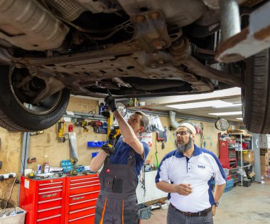 Team members at Ken's autos fixing underneath of car