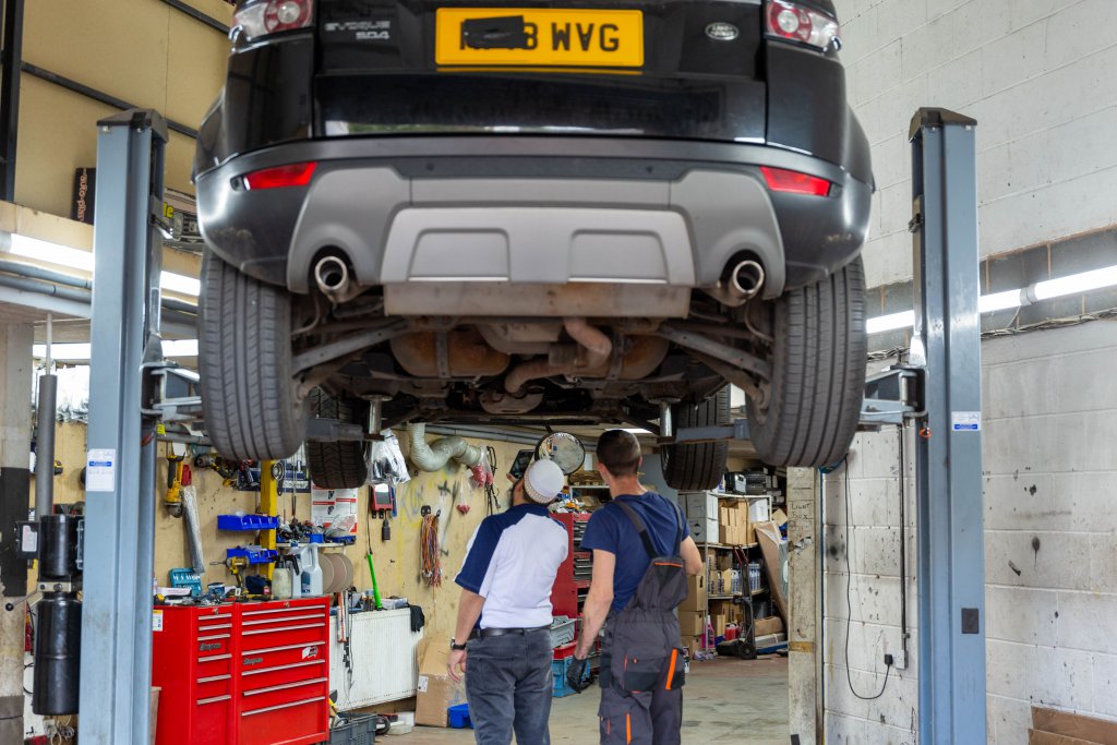 A car raised on the two-post lift in the workshop at Ken’s Auto Spares